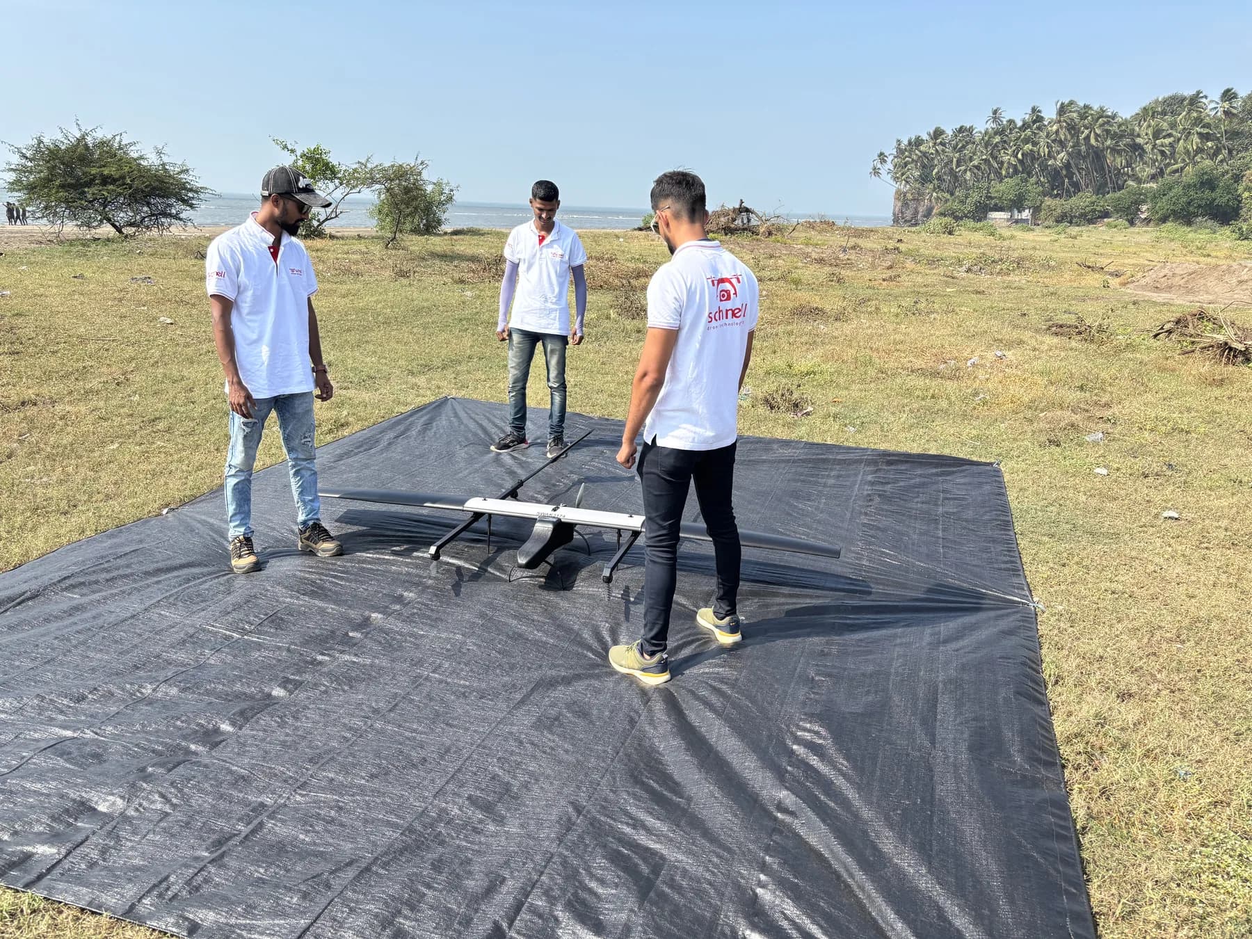 Schnell crew with a fixed-wing VTOL drone on a launch mat beside the coast