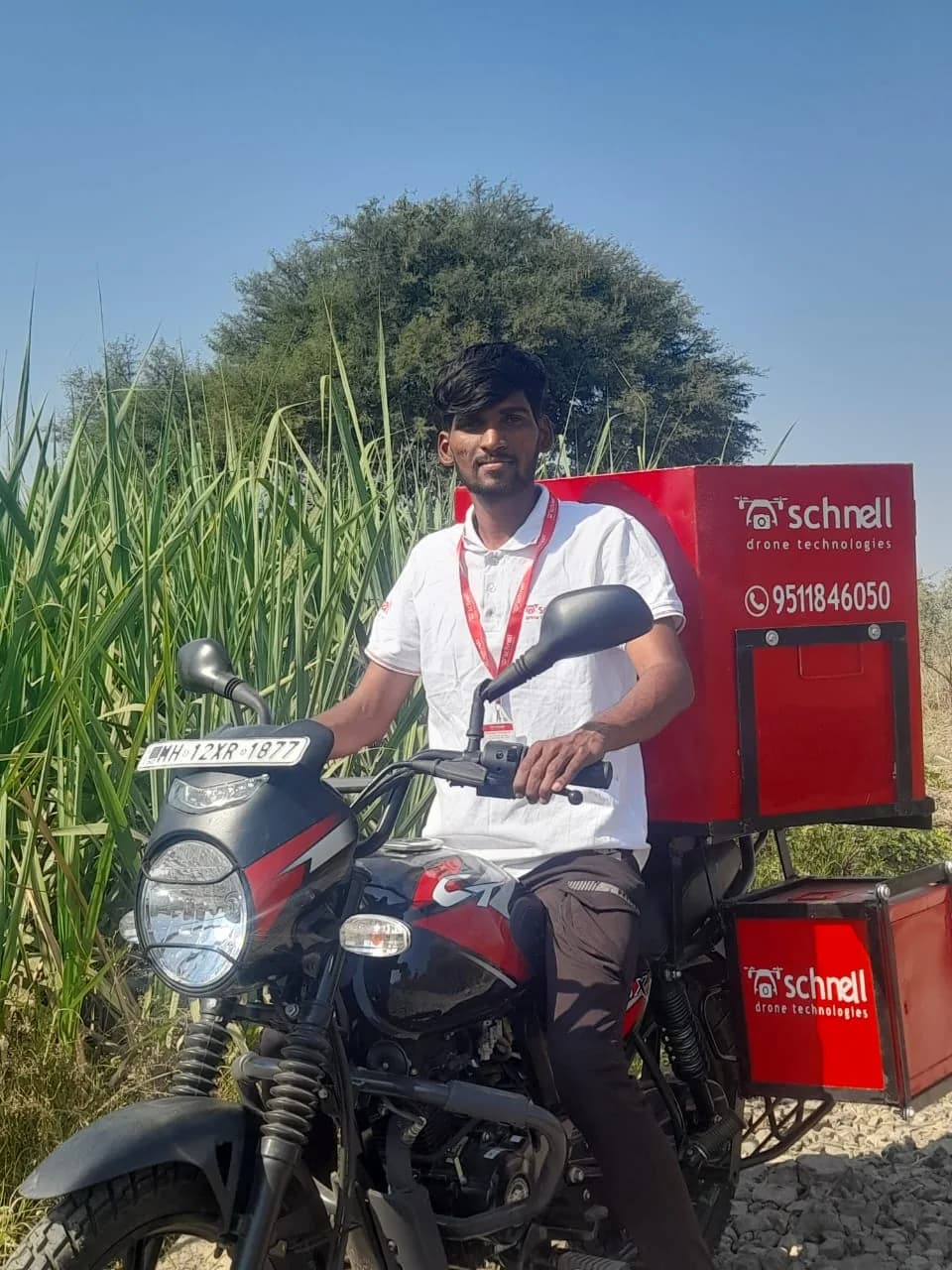 Schnell field operator with branded service panniers beside a standing crop