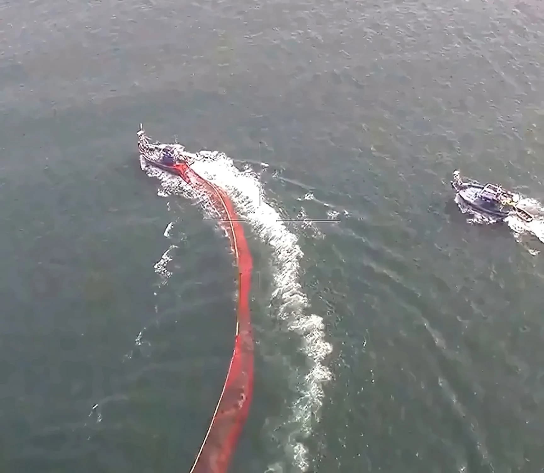 Two fishing vessels under way seen from 130 m above the Arabian Sea, one trailing a red net