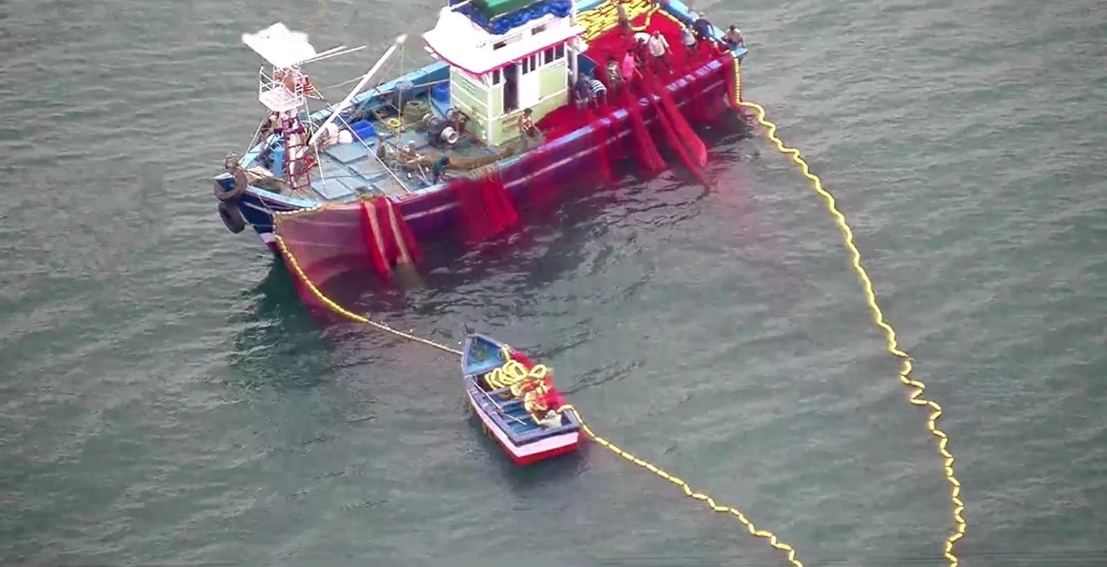 Purse seine net deployed in a wide loop around a trawler, seen from directly above