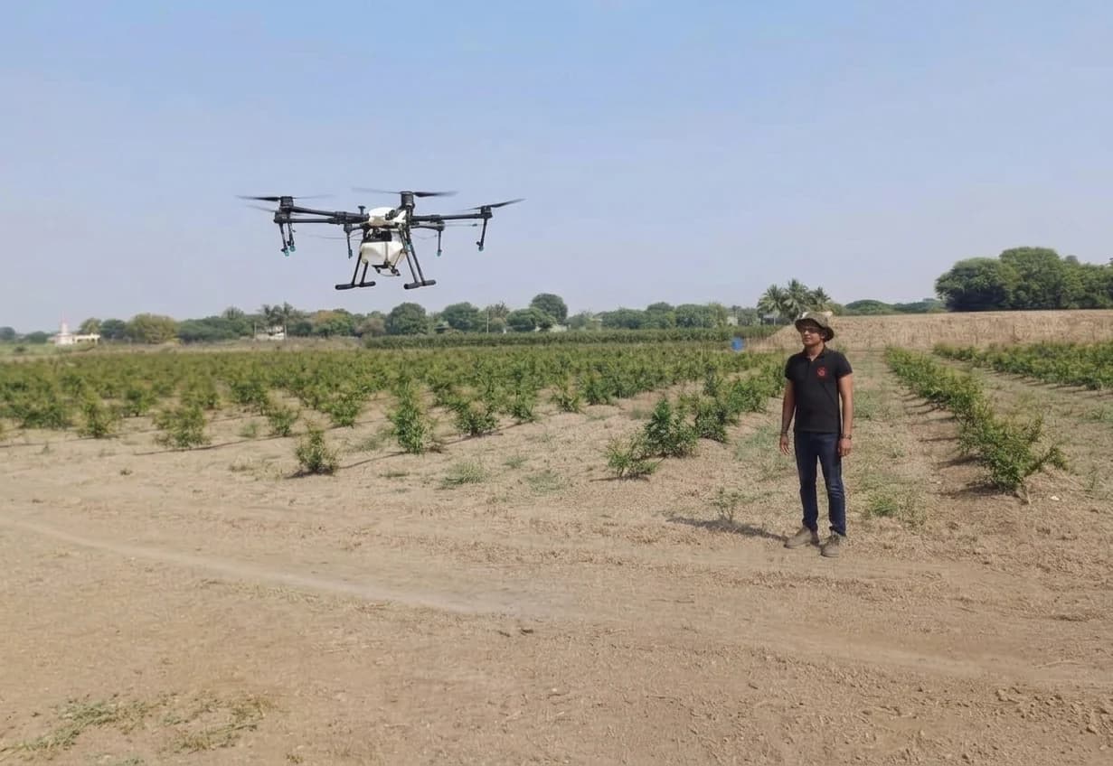 HIMALAYA spraying drone in flight over a young orchard as a Schnell operator watches from the field